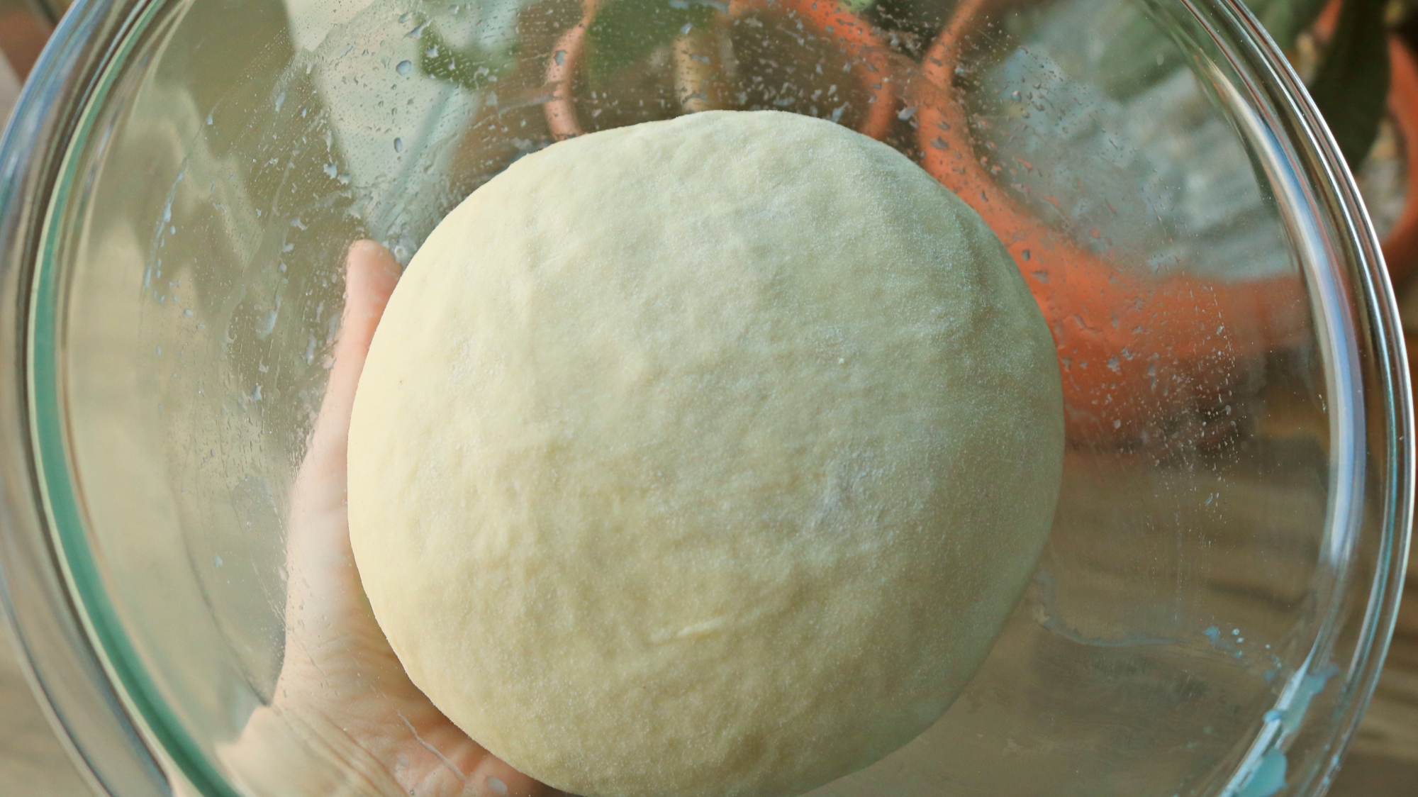 A ball of dough in a glass bowl.