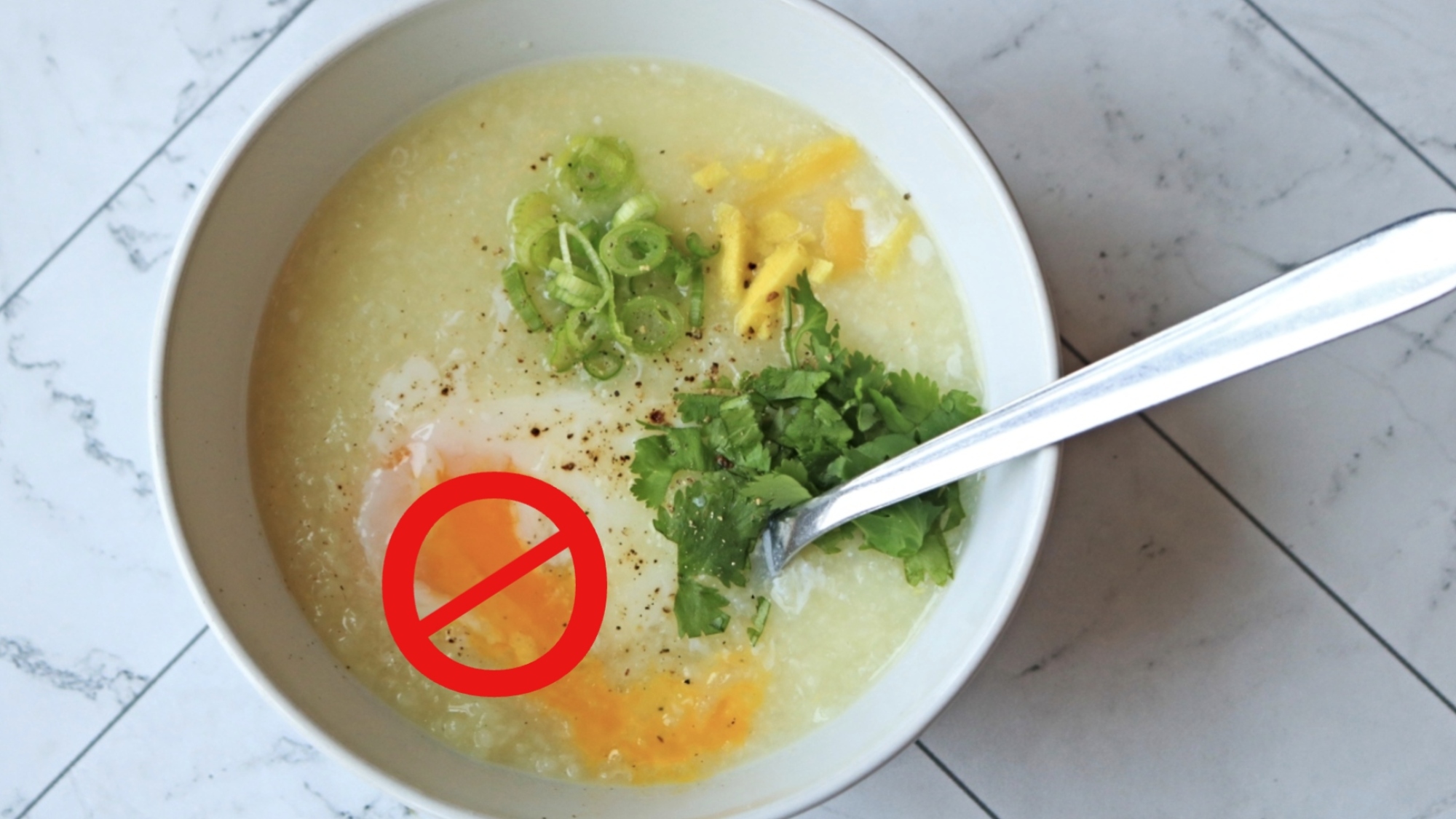 A bowl of Thai jok with a red "no" symbol over the egg